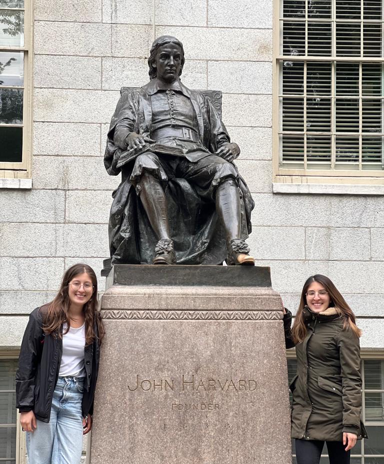 Two girls around the statue of John Harvard